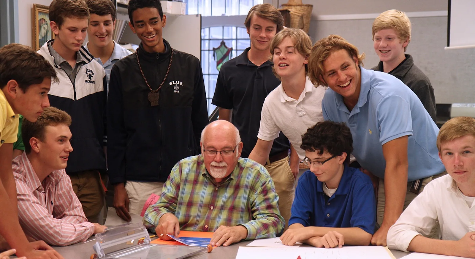 SLUH students gathered around a teacher in a classroom